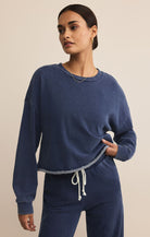 Woman wearing a blue lounge set against a beige background