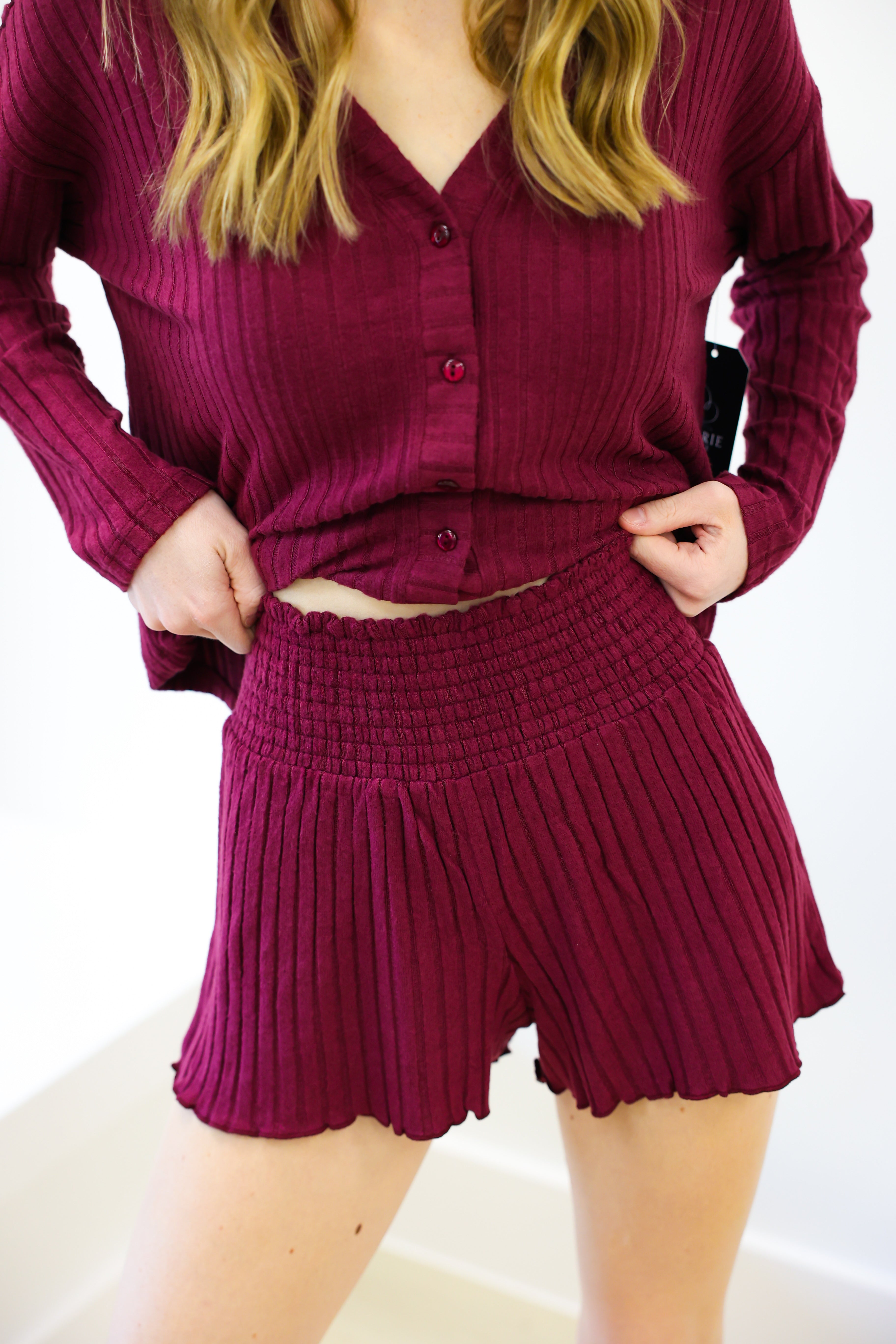 Person wearing a maroon ribbed outfit with a top and shorts on a white background