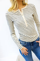 Person wearing a striped long-sleeve top and blue jeans on a white background