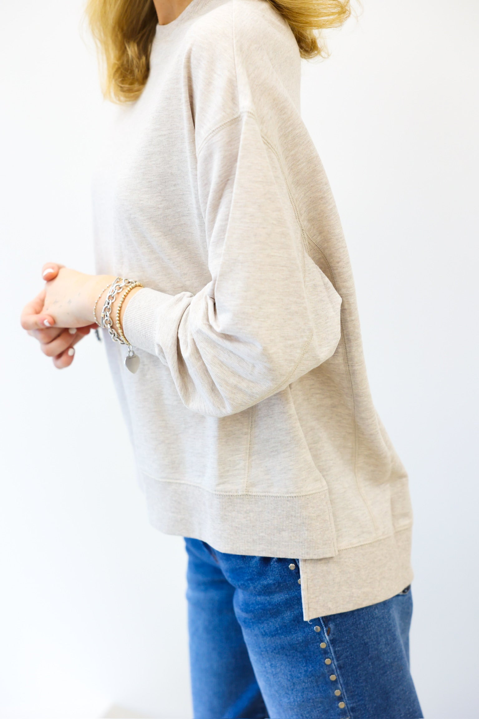 Person wearing a beige sweater and blue jeans on a white background