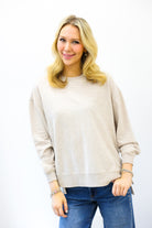 Woman wearing a beige sweater and blue jeans on a white background
