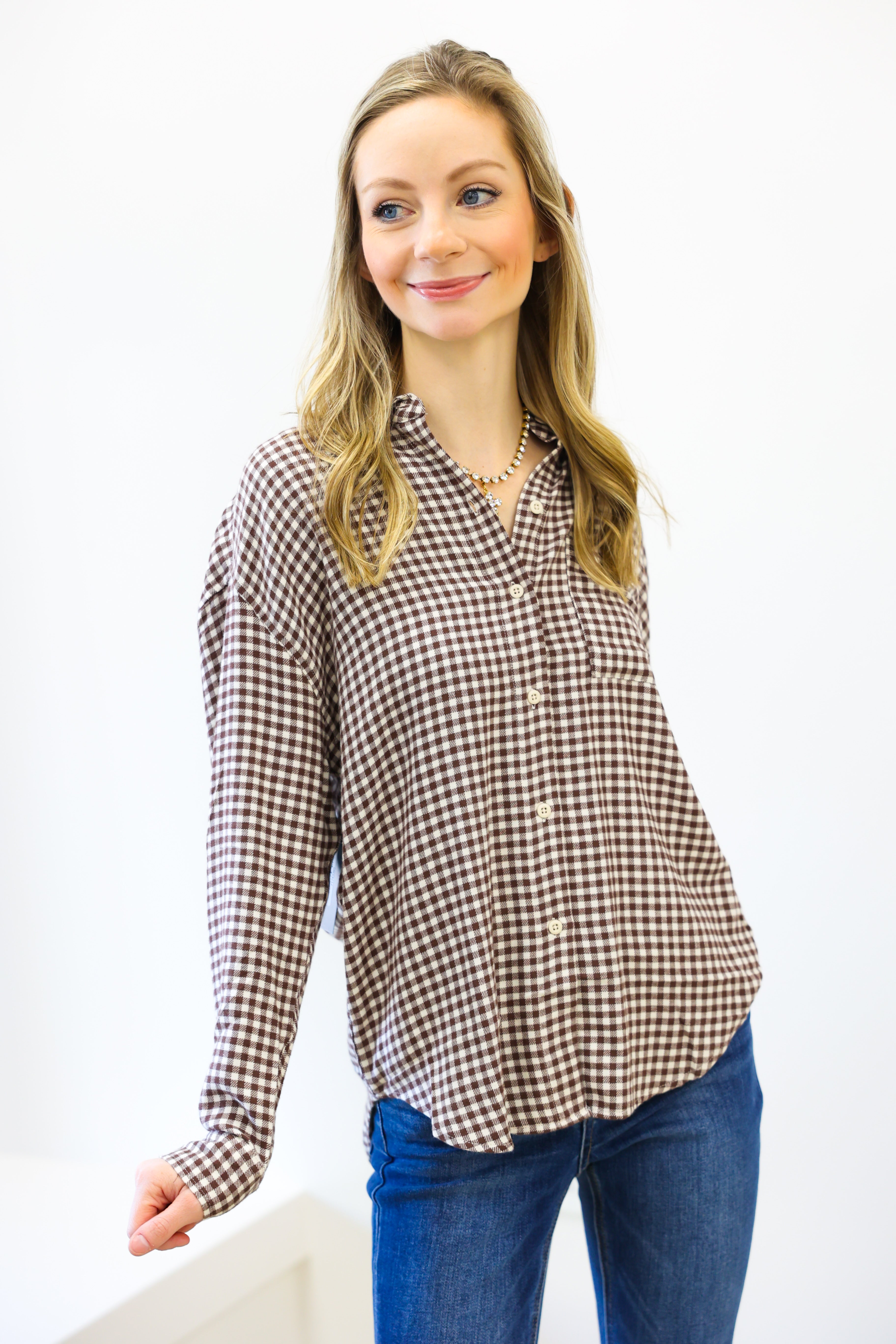 Woman wearing a brown and white checkered shirt with blue jeans on a white background