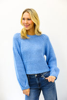 Woman wearing a blue sweater and jeans against a white background